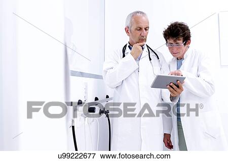 Stock Photo - Two doctors looking at digital tablet. Fotosearch