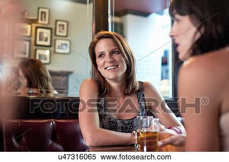 Two female adult friends drinking beer and chatting in traditional pub View Large Photo Image Stock Photography - Two female adult friends drinking beer and chatting in traditional pub. Fotosearch