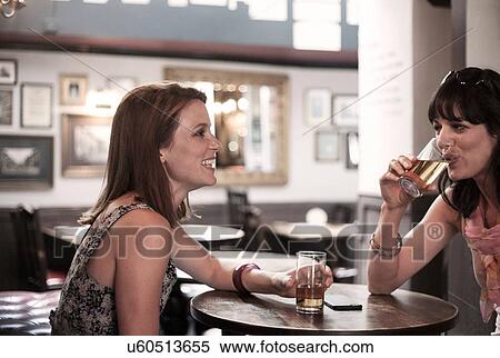 Two female adult friends drinking beer in traditional pub View Large Photo Image Stock Photography - Two female adult friends drinking beer in traditional pub. Fotosearch
