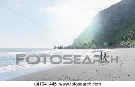 Stock Photograph - Two girls on beach, looking at view, Vik, Iceland. Fotosearch