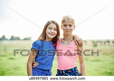 Stock Image - Two girls with arms around. Fotosearch