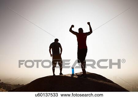 Two male friends, on top of mountain, in celebratory pose View Large Photo Image Stock Image - Two male friends, on top of mountain, in celebratory pose. Fotosearch