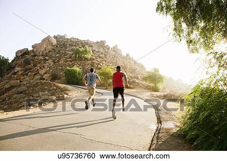 Two male friends running along mountain path, rear view View Large Photo Image Stock Image - Two male friends running along mountain path, rear view. Fotosearch