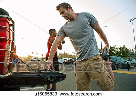 Stock Image - Two male friends, stretching, getting ready for workout. Fotosearch