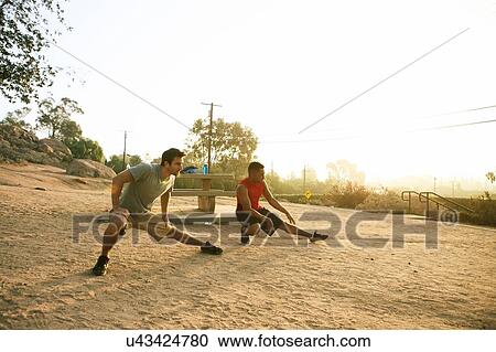 Stock Image - Two male friends working out together, outdoors. Fotosearch