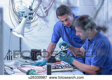 Stock Photo - Two male workers assembling electronics in electronics factory. Fotosearch