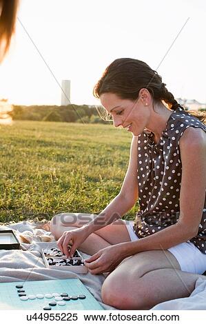 Stock Photography - Two mature female friends playing boardgame in park. Fotosearch