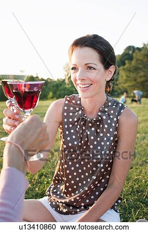 Two mature female friends toasting each other in park View Large Photo Image Stock Image - Two mature female friends toasting each other in park. Fotosearch