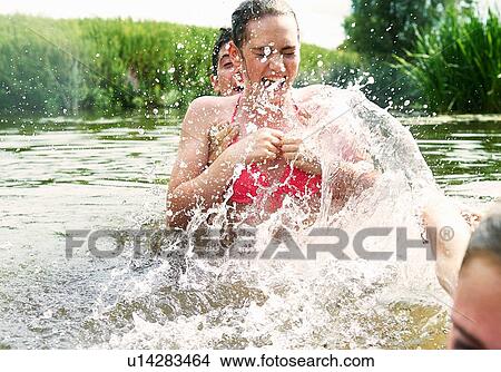 Two sisters and friend splashing around in rural lake View Large Photo Image Picture - Two sisters and friend splashing around in rural lake. Fotosearch