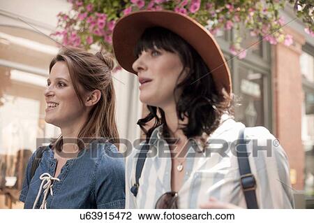 Stock Image - Two stylish women strolling on city street. Fotosearch