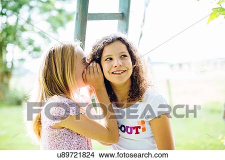 Two tween girls in garden whispering View Large Photo Image Picture - Two tween girls in garden whispering. Fotosearch