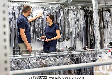 Two warehouse workers using digital tablet to stock take garments in distribution warehouse View Large Photo Image Stock Image - Two warehouse workers using digital tablet to stock take garments in distribution warehouse. Fotosearch