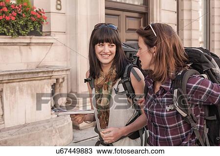 Two women backpackers chatting on city sidewalk View Large Photo Image Stock Image - Two women backpackers chatting on city sidewalk. Fotosearch