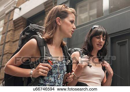 Two women backpackers chatting whilst strolling along street View Large Photo Image Picture - Two women backpackers chatting whilst strolling along street. Fotosearch
