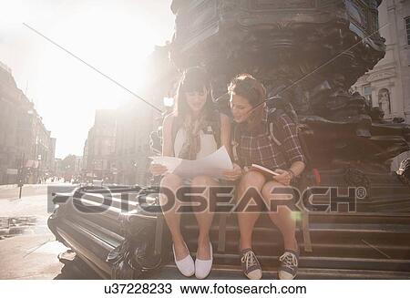 Two women backpackers sitting on steps looking at map and guide book, Picadilly Circus, London, UK View Large Photo Image Stock Image - Two women backpackers sitting on steps looking at map and guide book, Picadilly Circus, London, UK. Fotosearch