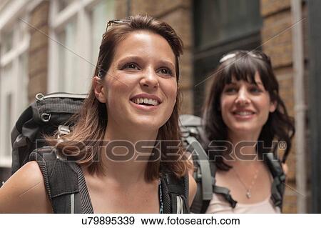Two women backpackers strolling along street View Large Photo Image Stock Photo - Two women backpackers strolling along street. Fotosearch