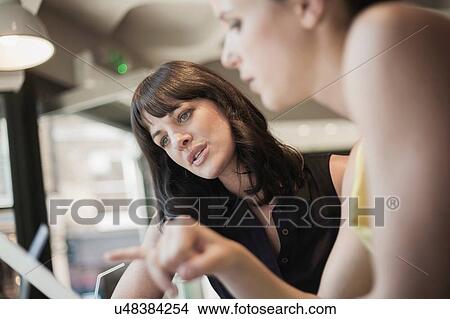 Two young brunette women sitting in a cafe talking having a business meeting View Large Photo Image Picture - Two young brunette women sitting in a cafe talking having a business meeting. Fotosearch