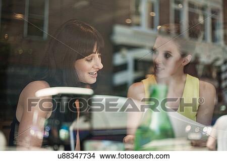 Two young brunette women sitting in a cafe talking having a business meeting View Large Photo Image Picture - Two young brunette women sitting in a cafe talking having a business meeting. Fotosearch