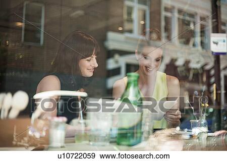 Stock Photo - Two young brunette women sitting in a cafe talking having a business meeting. Fotosearch