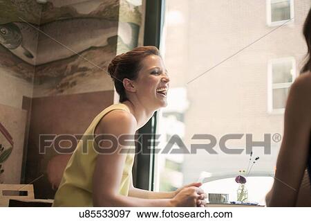 Two young brunette women sitting in a cafe talking and laughing View Large Photo Image Stock Photo - Two young brunette women sitting in a cafe talking and laughing. Fotosearch