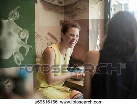 Stock Photograph - Two young brunette women sitting in a cafe talking. Fotosearch
