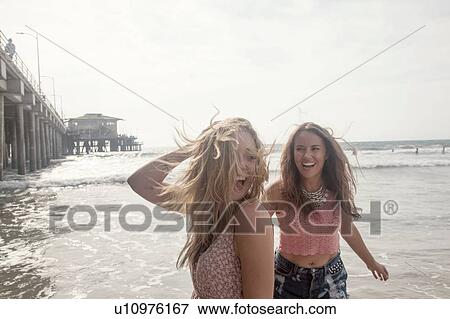 Stock Photo - Two young women having fun on windwept beach, Santa Monica, California, USA. Fotosearch