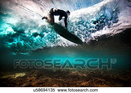 Stock Photography - Underwater view of surfer falling through water after catching a wave on a shallow reef in Bali, Indonesia. Fotosearch
