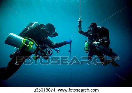 Stock Image - Underwater view of two technical divers using rebreathers device to locate shipwreck, Lombok, Indonesia. Fotosearch