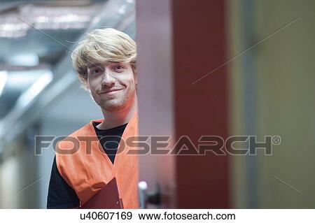 View through doorway of young man wearing high visability vest looking at camera smiling View Large Photo Image Stock Photo - View through doorway of young man wearing high visability vest looking at camera smiling. Fotosearch
