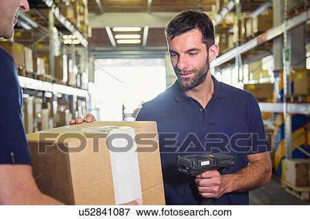 Stock Photo - Warehouse worker using barcode scanner on cardboard box in distribution warehouse. Fotosearch