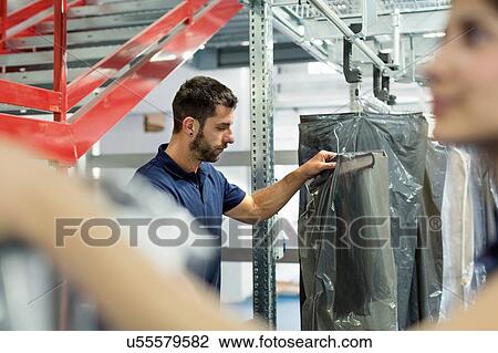 Stock Image - Warehouse workers collecting garment orders in distribution warehouse. Fotosearch