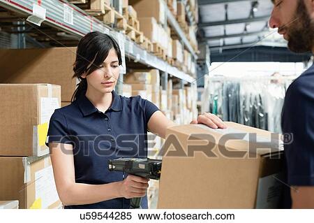 Stock Photography - Warehouse workers using barcode scanner on box in distribution warehouse. Fotosearch
