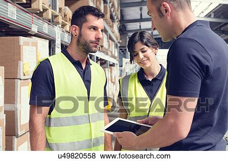Warehouse workers using digital tablet in distribution warehouse View Large Photo Image Stock Photo - Warehouse workers using digital tablet in distribution warehouse. Fotosearch