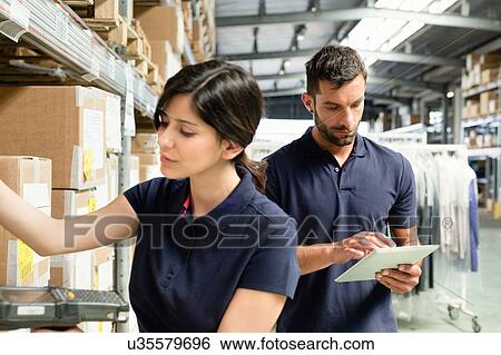 Warehouse workers using digital tablet to prepare order in distribution warehouse View Large Photo Image Stock Photograph - Warehouse workers using digital tablet to prepare order in distribution warehouse. Fotosearch