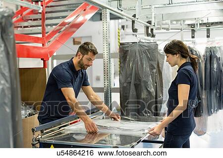 Warehouse workers wrapping garment stock in plastic in distribution warehouse View Large Photo Image Stock Photograph - Warehouse workers wrapping garment stock in plastic in distribution warehouse. Fotosearch