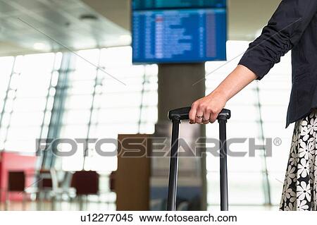 Woman with suitcase, waiting by departures board View Large Photo Image Stock Photography - Woman with suitcase, waiting by departures board. Fotosearch