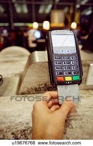 Stock Photo - Womans hand using credit card machine for restaurant payment. Fotosearch