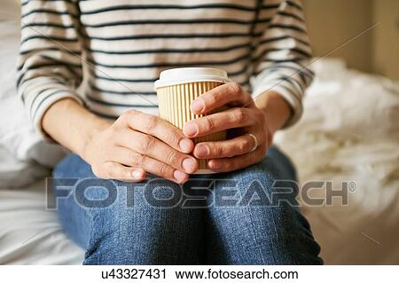 Womans hands holding takeaway coffee on bed View Large Photo Image Stock Image - Womans hands holding takeaway coffee on bed. Fotosearch