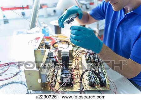 Stock Image - Worker assembling electronics in electronics factory. Fotosearch