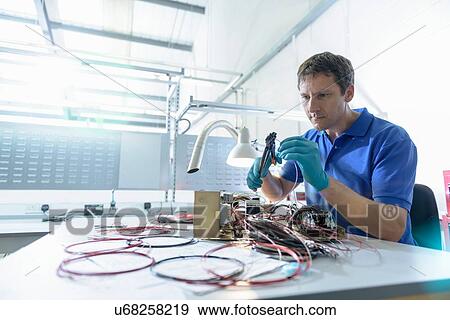 Stock Photo - Worker assembling electronics in electronics factory. Fotosearch