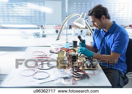 Stock Photo - Worker assembling electronics in electronics factory. Fotosearch