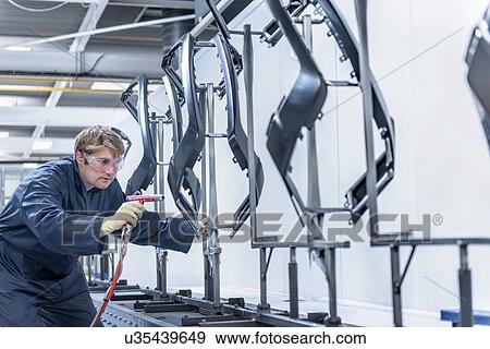Worker cleaning automotive parts in spray paint factory View Large Photo Image Stock Photo - Worker cleaning automotive parts in spray paint factory. Fotosearch