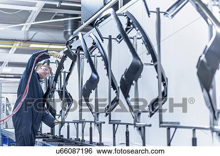 Stock Photograph - Worker cleaning automotive parts in spray paint factory. Fotosearch
