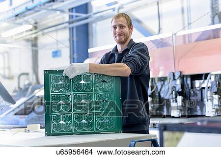 Picture - Worker cutting circuit boards in circuit board factory, portrait. Fotosearch