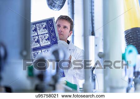 Stock Image - Worker inspecting circuit board by processing plant in circuit board factory. Fotosearch