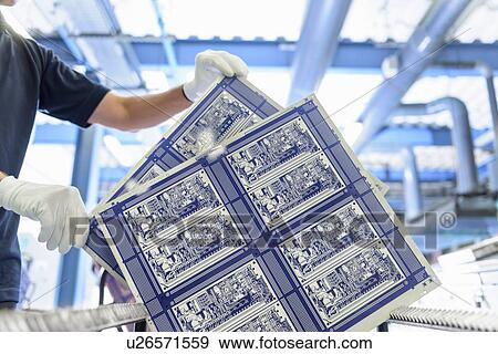 Stock Photo - Worker inspecting circuit board in circuit board factory. Fotosearch