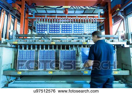 Stock Photograph - Worker loading circuit boards into processing machine in circuit board factory. Fotosearch
