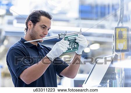 Stock Image - Worker measuring cut circuit board in circuit board factory. Fotosearch