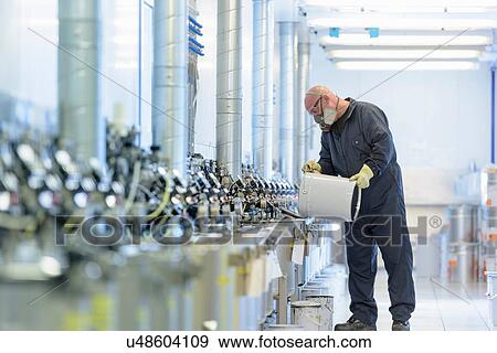 Stock Photo - Worker mixing paint in automotive parts spray paint factory. Fotosearch