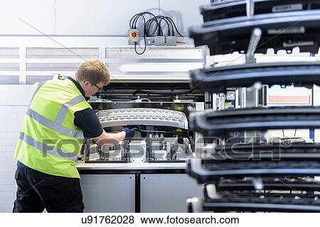 Stock Photo - Worker with test rig in spray paint factory. Fotosearch